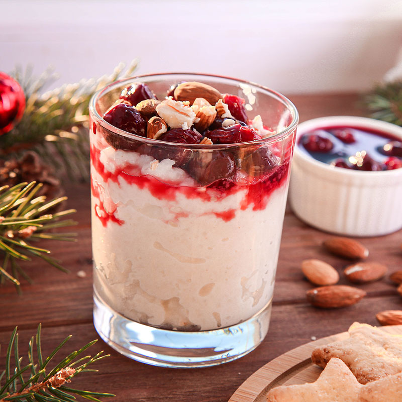 Glas mit dänischem Weihnachtsdessert Risalamande, serviert mit Kirschsoße und gehackten Mandeln.