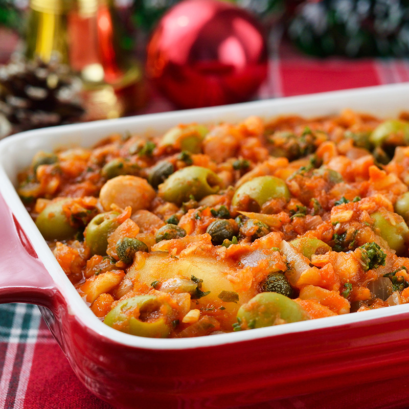 Mexikanisches Weihnachtsgericht Bacalao a la Vizcaína mit Oliven, Kapern und Tomatensauce in einer roten Auflaufform.