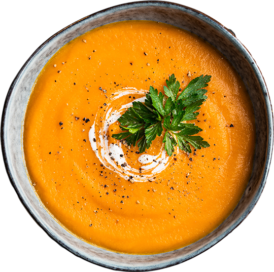 Schale mit cremiger Kürbissuppe, garniert mit einem Klecks Sahne und frischer Petersilie.