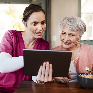Pflegekraft zeigt einer Seniorin die App EASY ORDER für die Verpflegung in Pflegeeinrichtungen