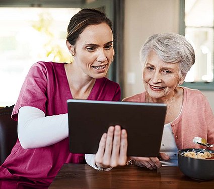 Pflegekraft zeigt einer Seniorin die App EASY ORDER für die Verpflegung in Pflegeeinrichtungen