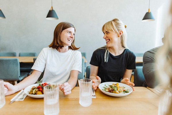 Zwei Frauen amüsieren sich in der Mittagspause bei einem leckeren und nachhaltigen Snack von apetito catering