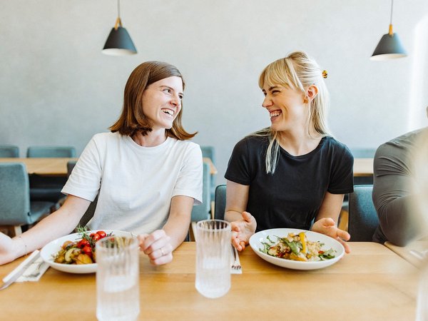 Zwei Frauen amüsieren sich in der Mittagspause bei einem leckeren und nachhaltigen Snack von apetito catering