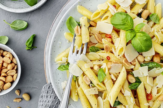 Nudeln mit Chili, Parmesan und Nüssen auf einem Teller mit frischen Kräutern