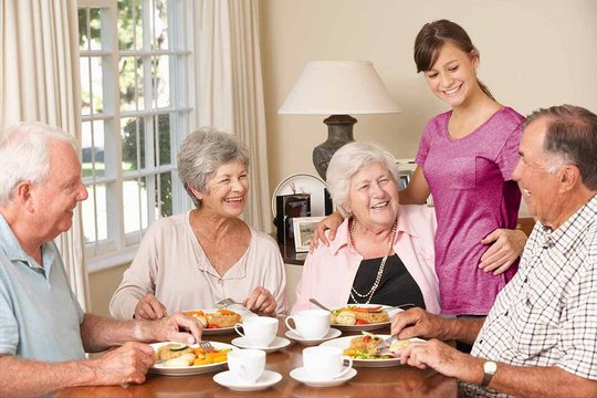 Pflegekraft in einem lustigen Gespräch mit glücklichen Senioren durch die digitale Servierliste