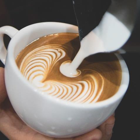 Leckerer, frischer Kaffee wird mit Milch in Herzform angerichtet
