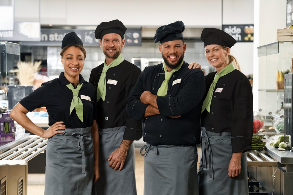 Vier Mitarbeiter von apetito catering lächeln und sind zufrieden mit ihrer Arbeit