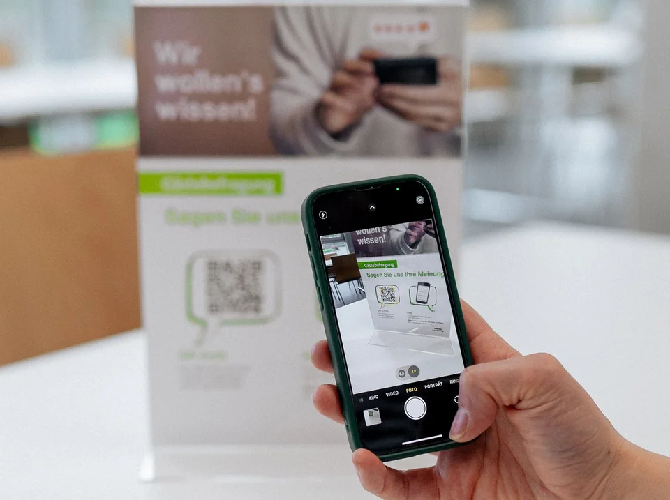 Jemand scannt mit seinem Handy den QR-Code von einem Aufsteller