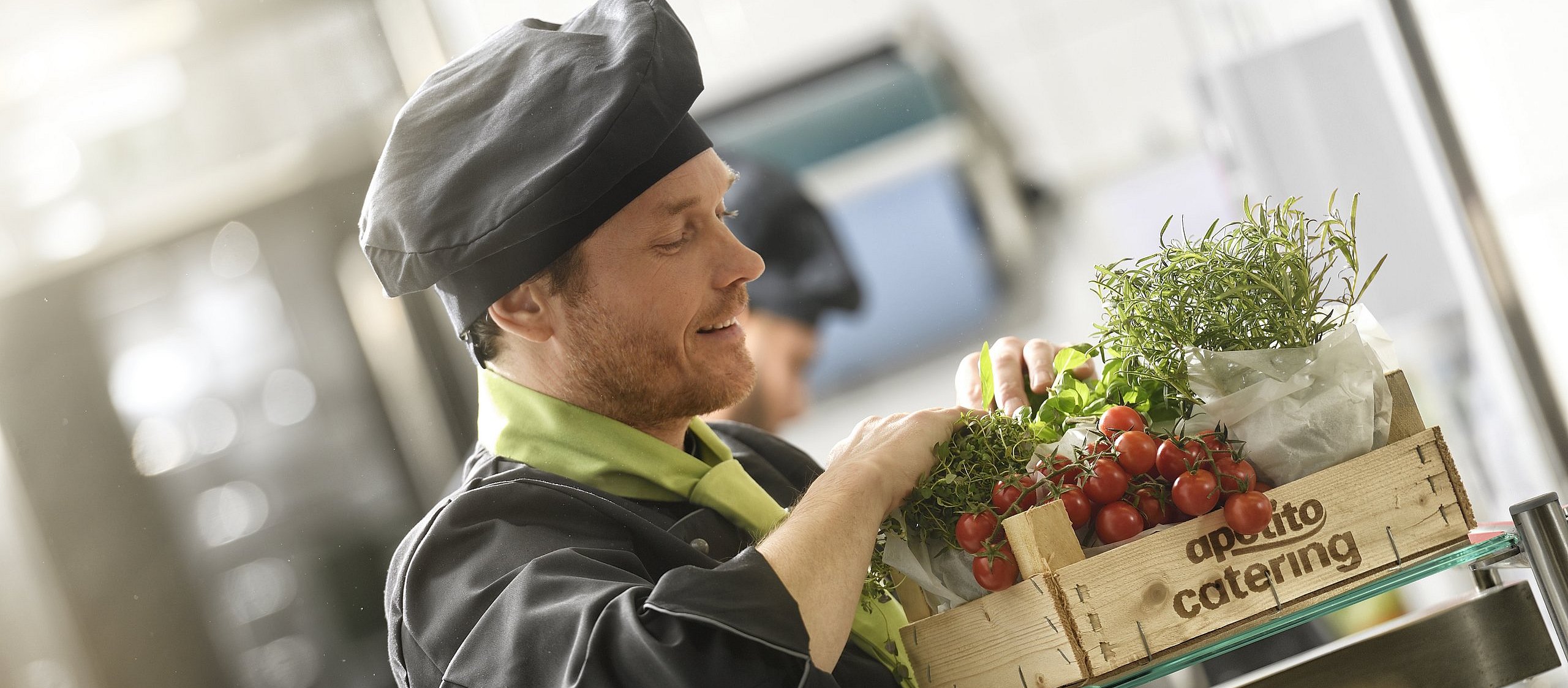 Holzkiste gefüllt mit frischen Tomaten aus der Region und leckeren Kräutern mit dem Schriftzug apetito catering