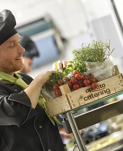 Holzkiste gefüllt mit frischen Tomaten aus der Region und leckeren Kräutern mit dem Schriftzug apetito catering