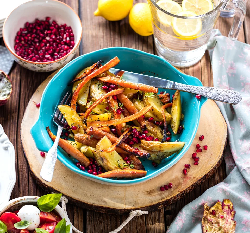 Ofengemüse mit knusprigen Kartoffelspalten, Karotten, Granatapfelkernen und frischer Zitronenlimonade