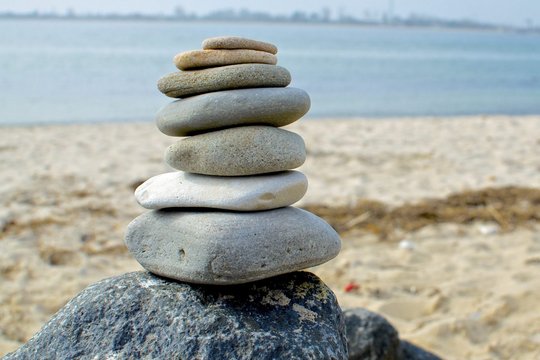 Gestapelte Steine am Strand symbolisieren Balance in der Unternehmenskultur