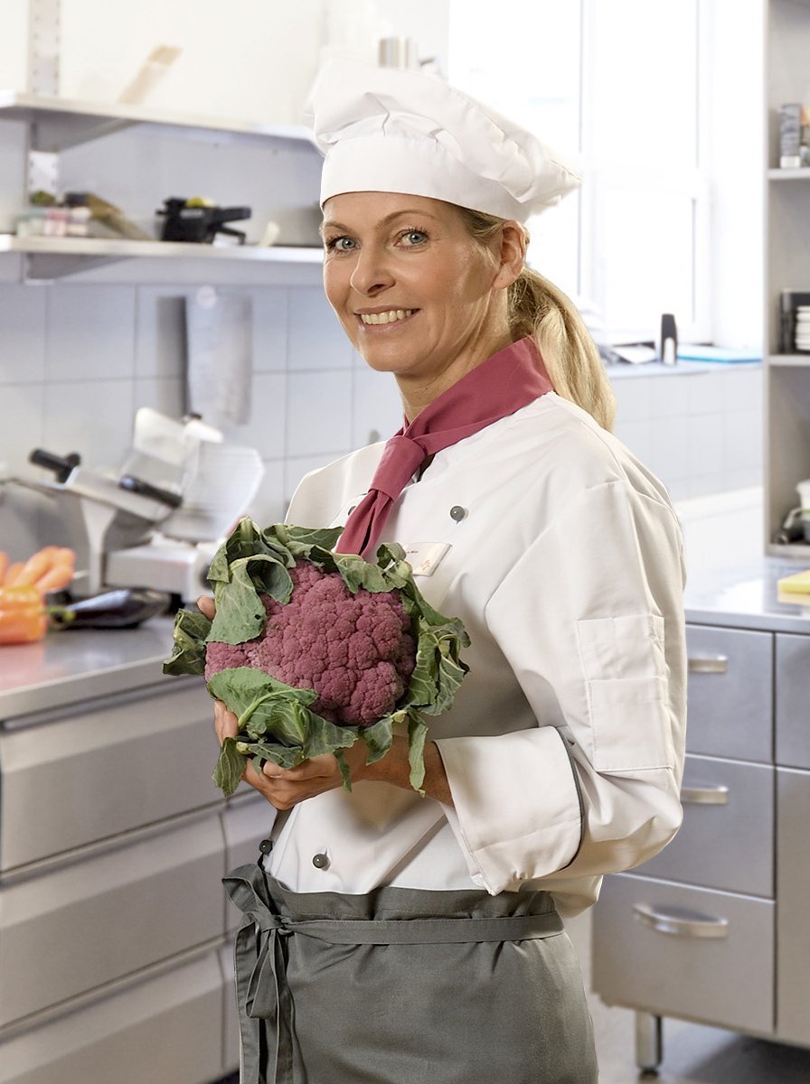 Care Gastronomie Mitarbeiterin mit frischem Blumenkohl in der Hand steht in der Küche
