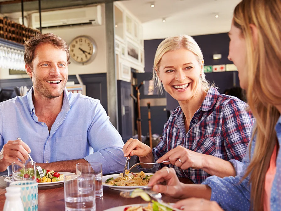 Mitarbeiter genießen das Mittagessen mit Pasta und einem frischen Salat im Betriebsrestaurant